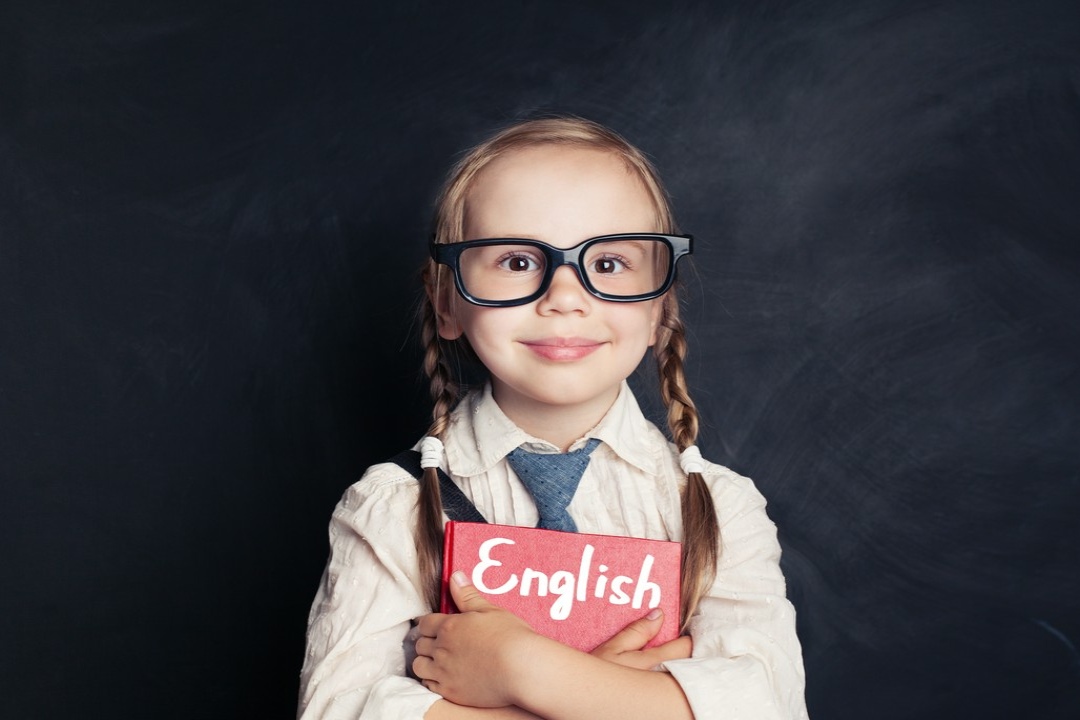 dziewczynka w okularach trzyma książkę do nauki angielskiego