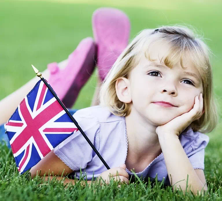 dziewczynka leżąca na trawie z flagą w ręku